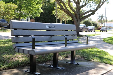 An example of the composite bench at a city park. The bench is grey and has a commemoration plaque with room for a customized message.